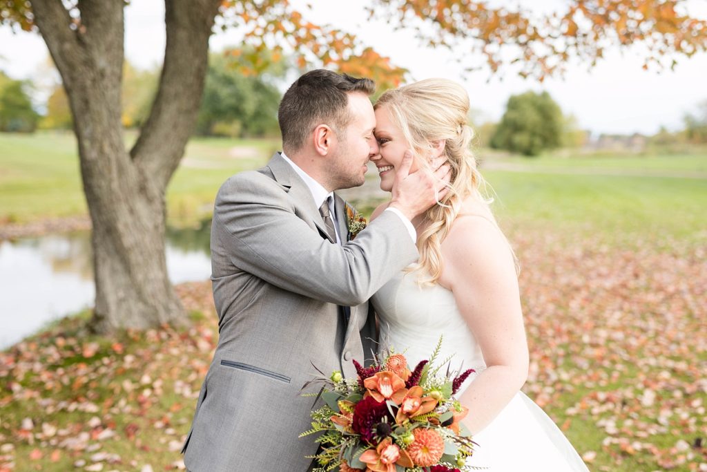 couple kissing under a yellow and orange tree at their October wedding at a wedding at Lake Wissota Golf & Events
