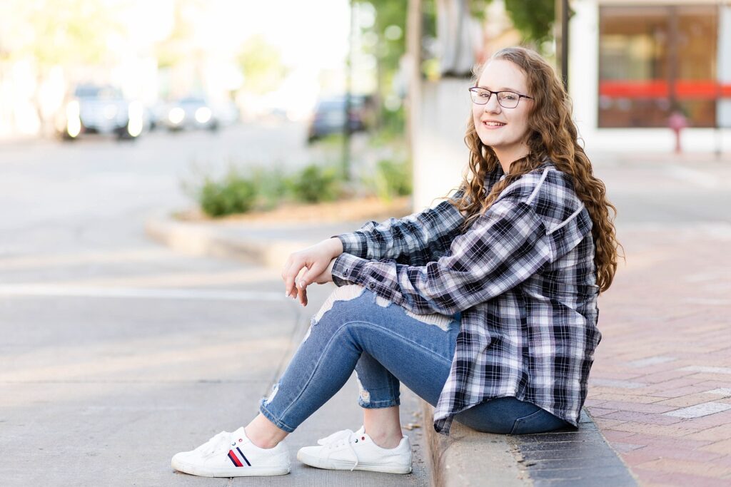 girl sitting on a curb for her eau claire senior photos